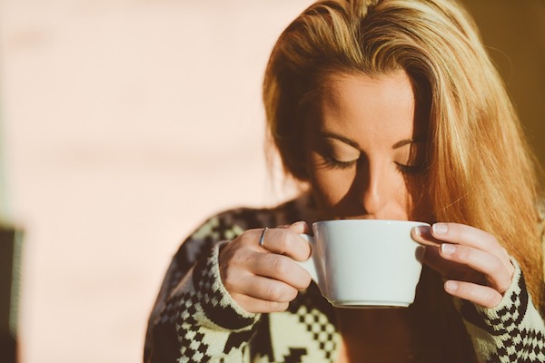 A woman holding a cup of unfiltered coffee.