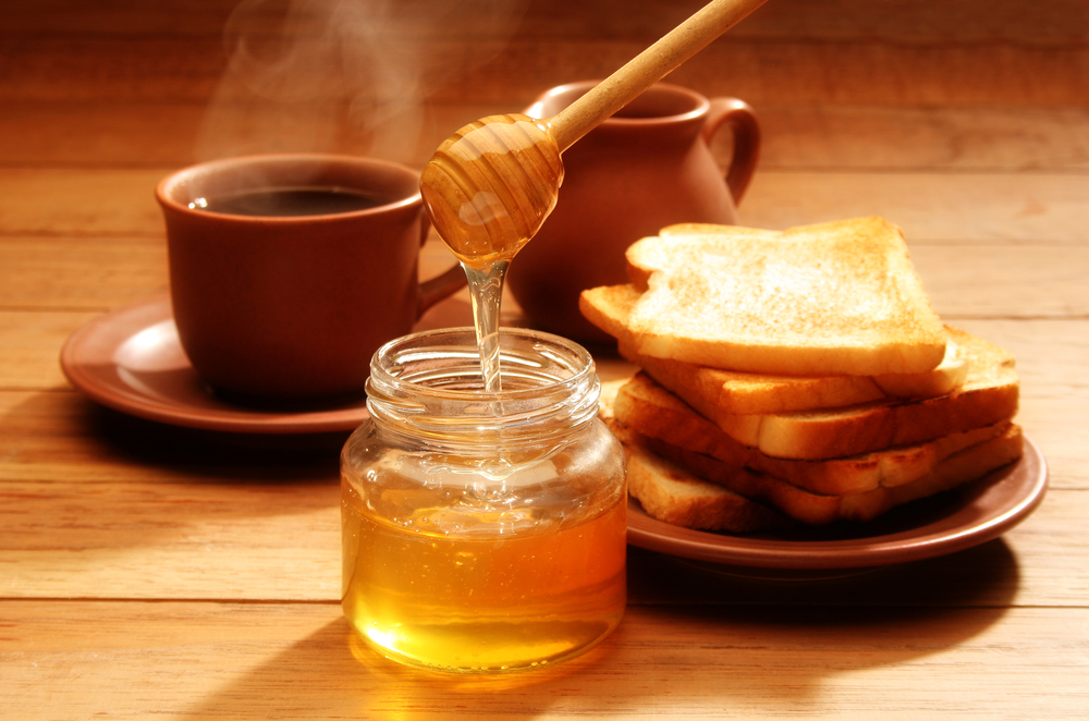 Honey in a jar, 2 cups of coffee and a saucer with bread loaves