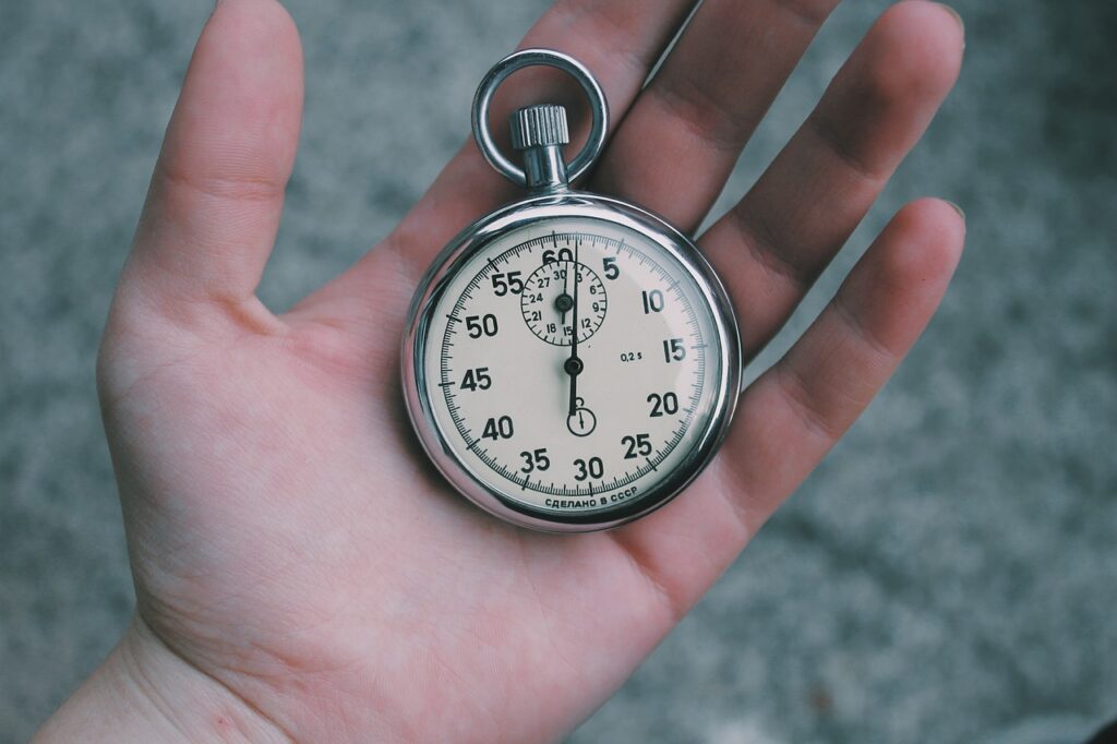 A silver mechanical watch placed in a palm of a hand