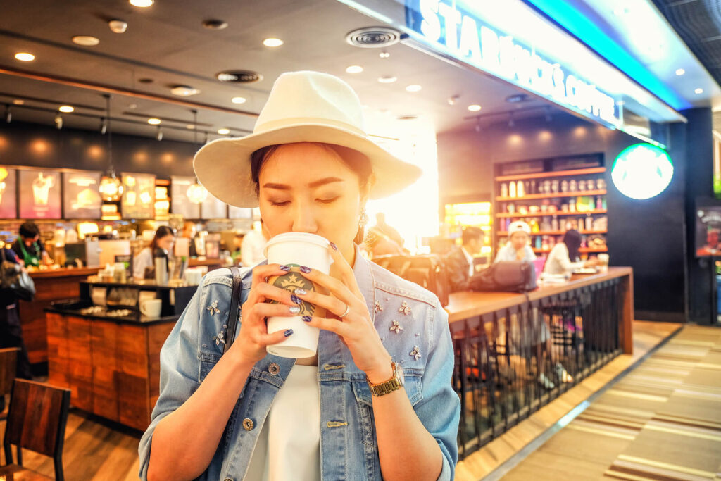 A woman drinking starbucks drinks inside the coffee shop.