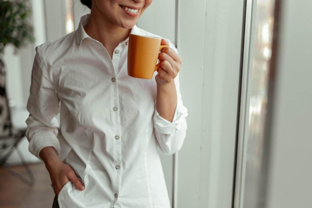 Asian woman smiling while holding a cup of  coffee