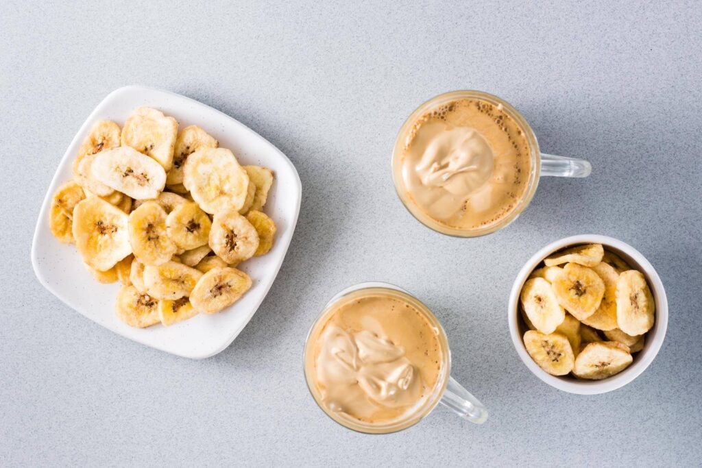 Two cups with coffee and a two bowls of frozen banana