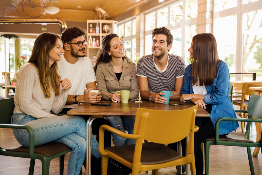 Friends talking and drinking coffee in a cafe - Why we love drinking coffee