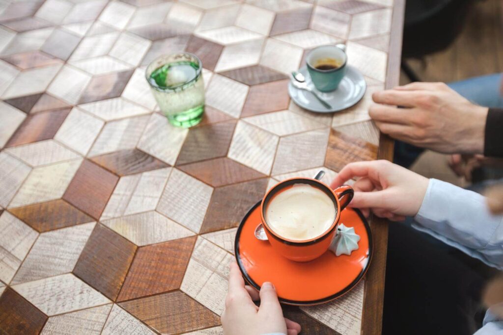  man and woman having cups of coffee sitting at table with ornamental wood desk