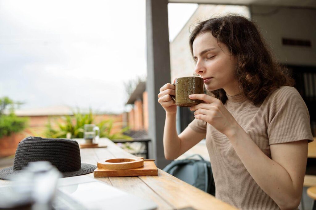 Smiling pretty woman drinking coffee in cafe outdoors