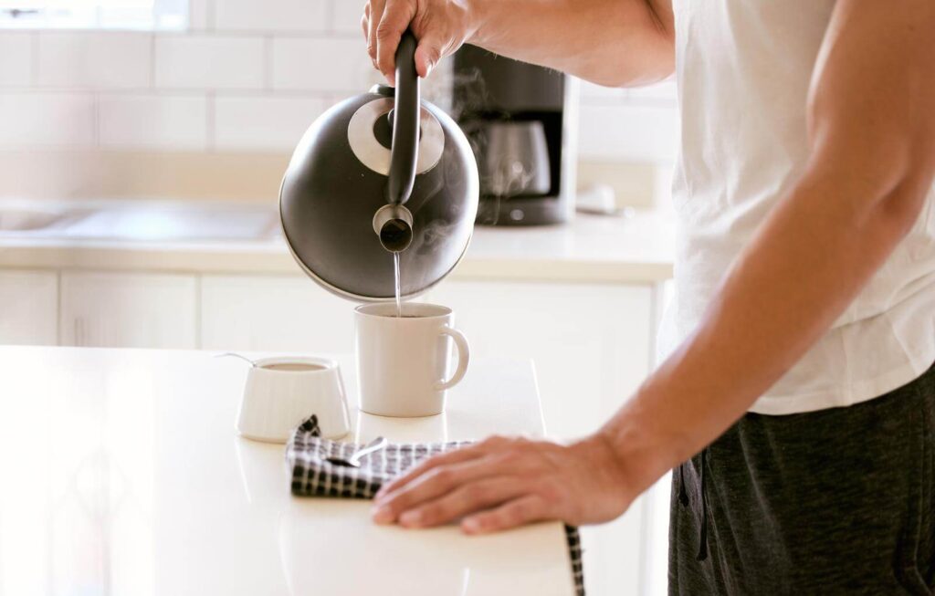 Man pouring water into a cup of tea