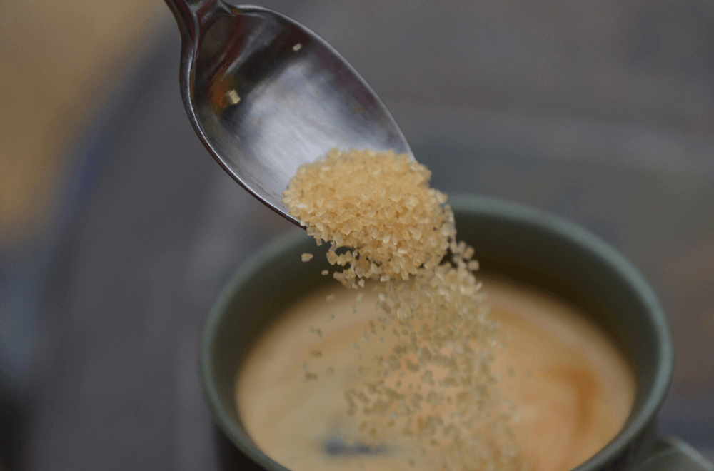 Adding sugar in a cup of coffee