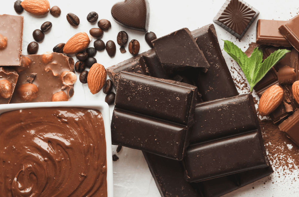 Coffee beans with dark chocolate bars and almond on white table