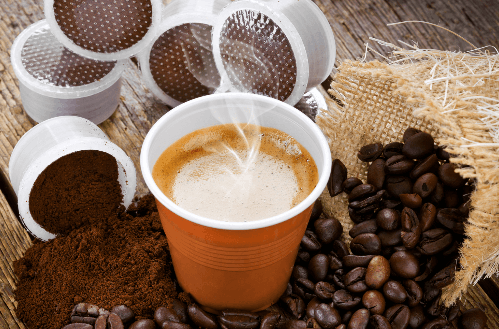 Hot cup of coffee with coffee beans and ground coffee beside