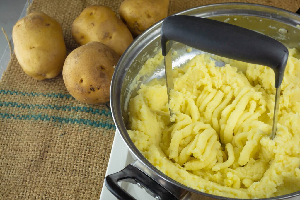 Crushing boiled potatoes with a potato masher