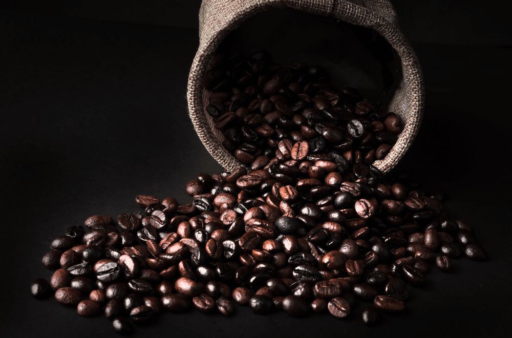 Spill dark coffee beans from a sack