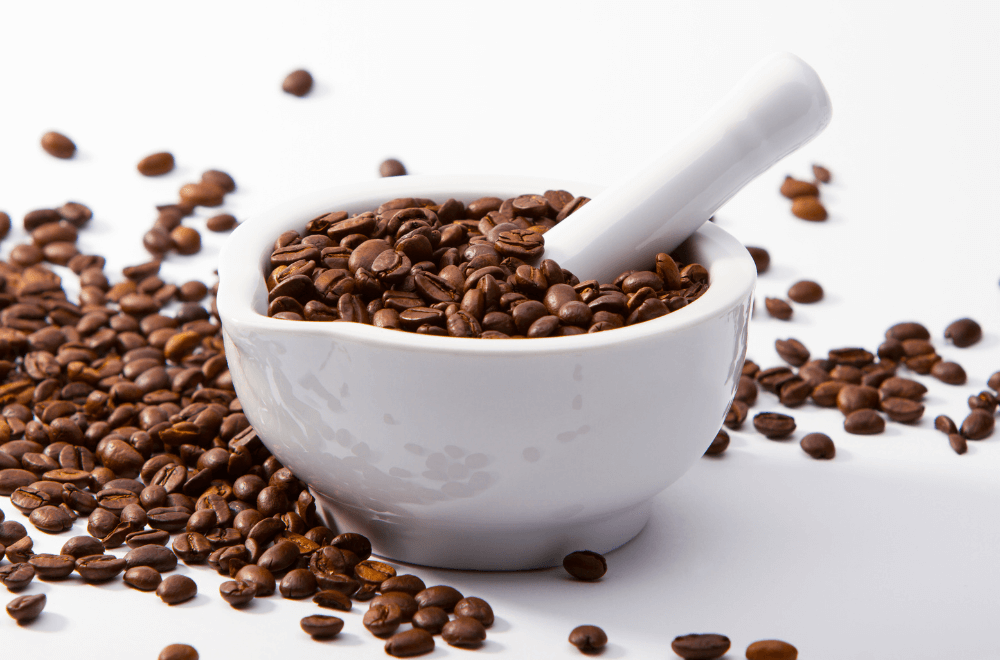 Mortar and pestle full of coffee beans on the white table