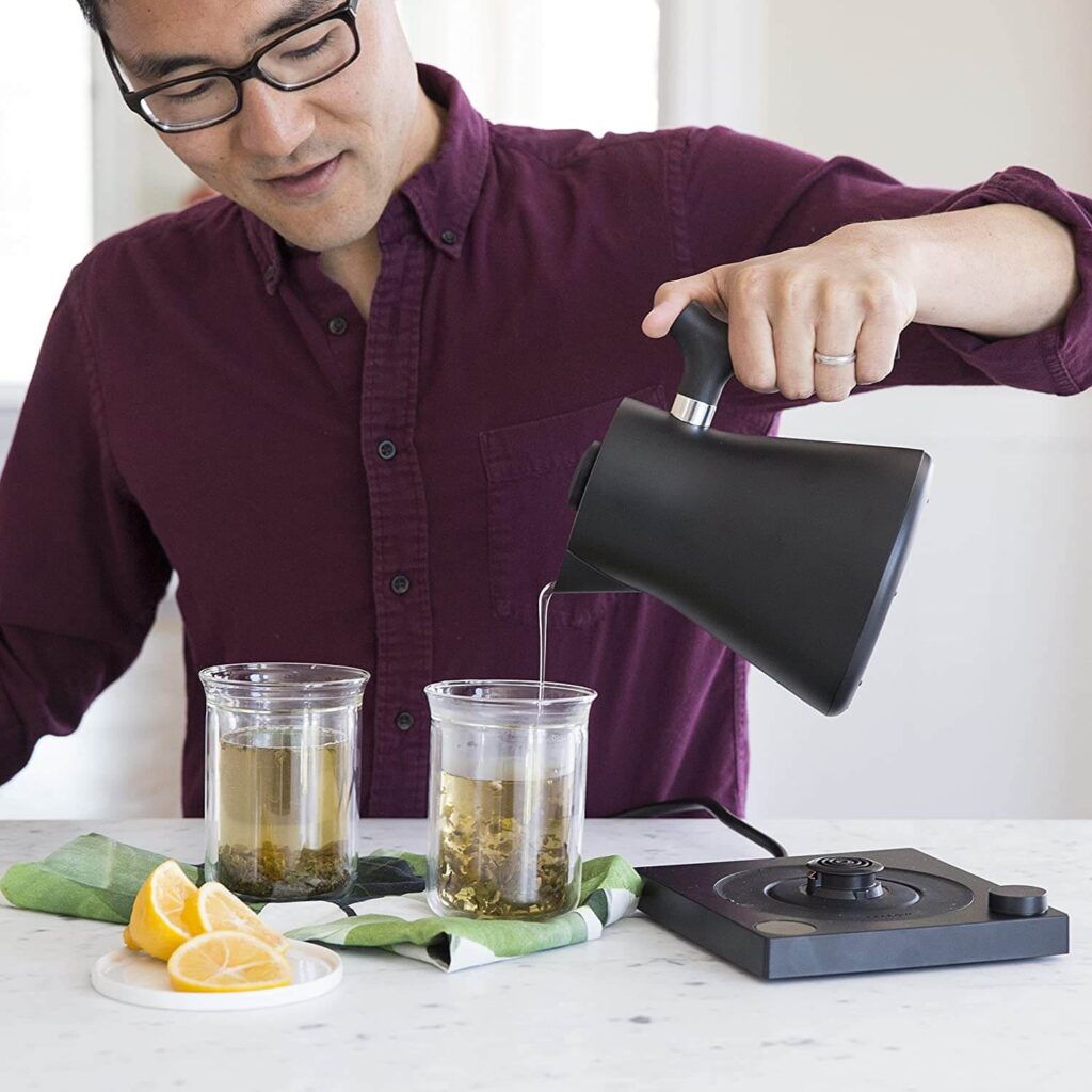 Asian man pouring tea using Fellow Corvo electric kettle