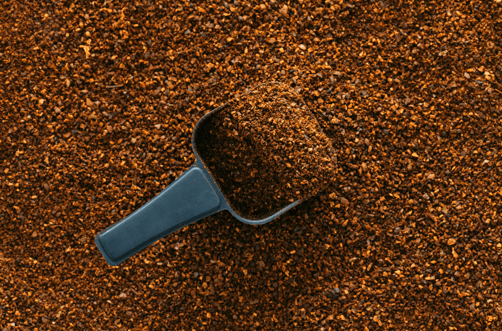 Plastic scoops rest in ground coffee