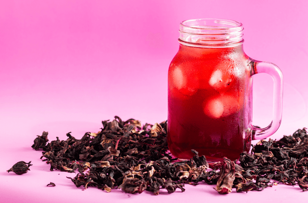 A large jar of cold agua de jamaica with dried leaves