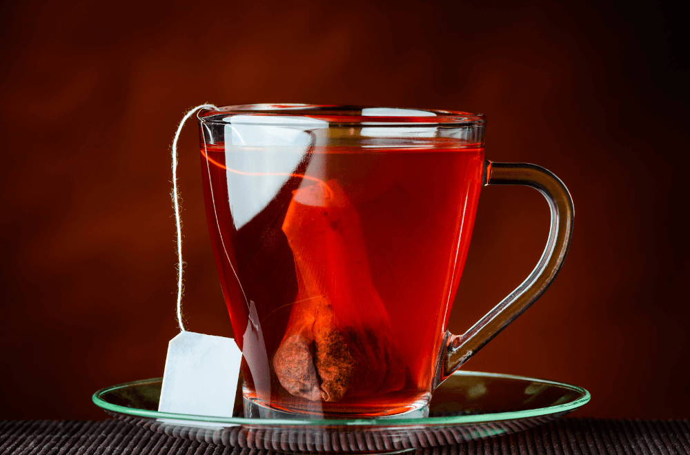A glass tea cup with hibiscus tea bag