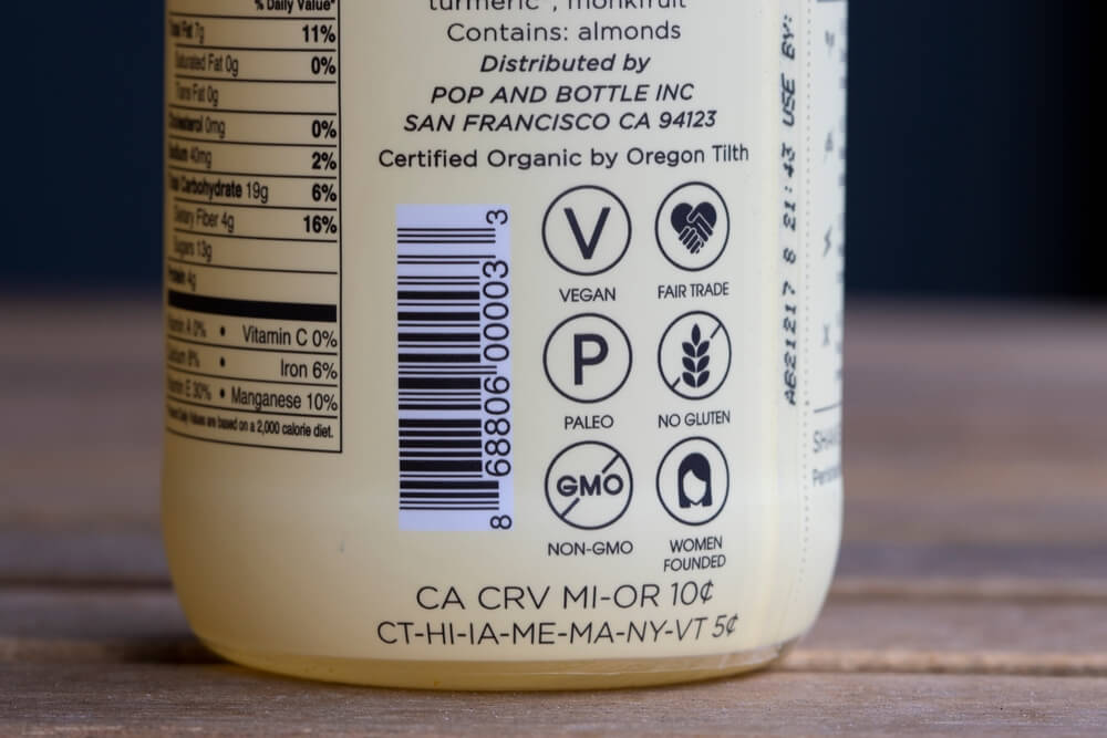 Various labelings seen on a bottle of Pop and Bottle brand almond latte