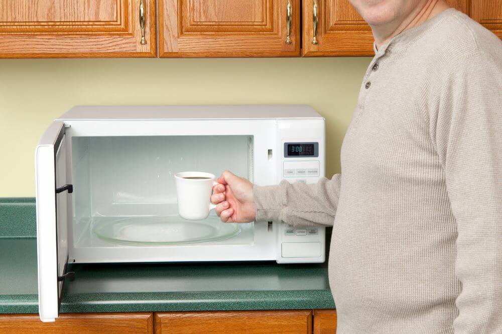 Man reheating coffee in microwave