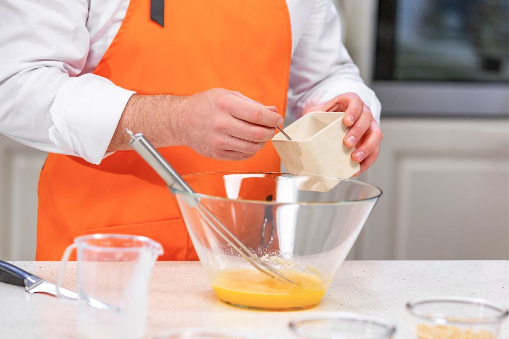 The chef add sugar to beaten egg