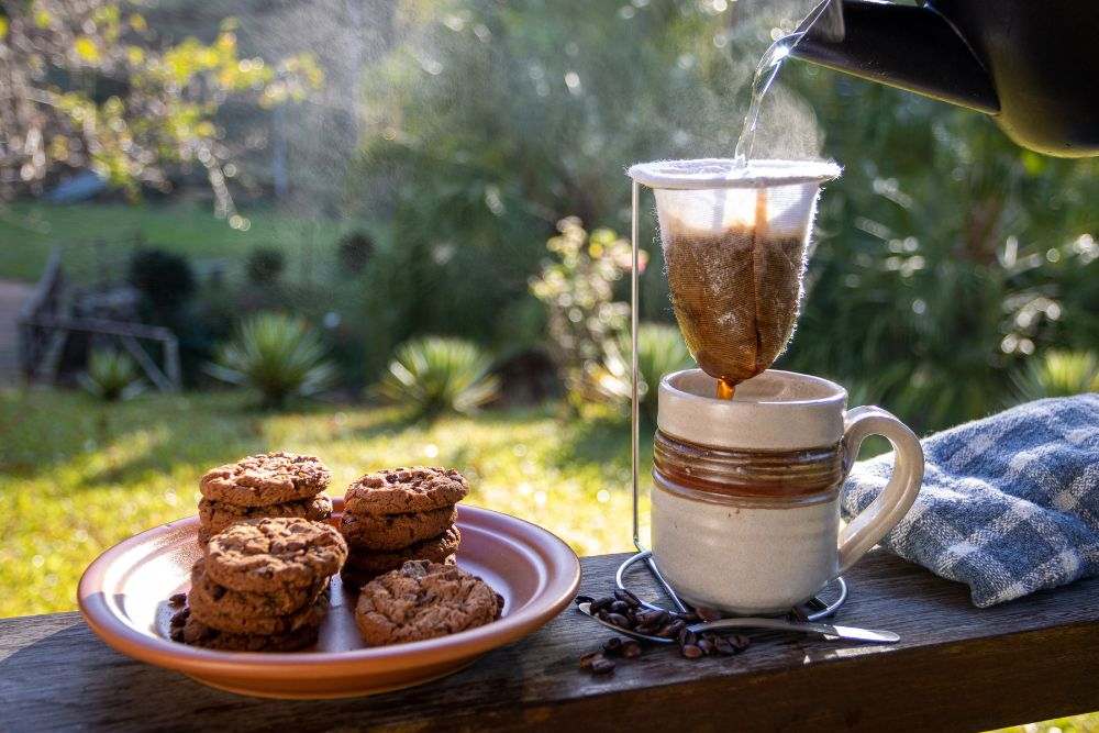 Breakfast with coffee being made on the spot in a cloth filter accompanied with chocolate chip cookies on a beautiful morning on the farm