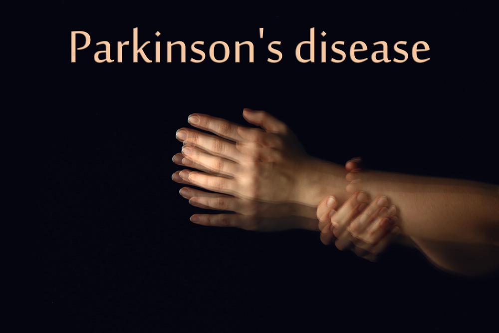 Trembling hands and text PARKINSON'S DISEASE on dark background
