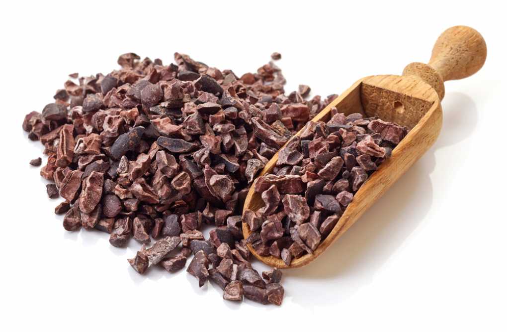 Heap of cacao nibs, isolated on white background