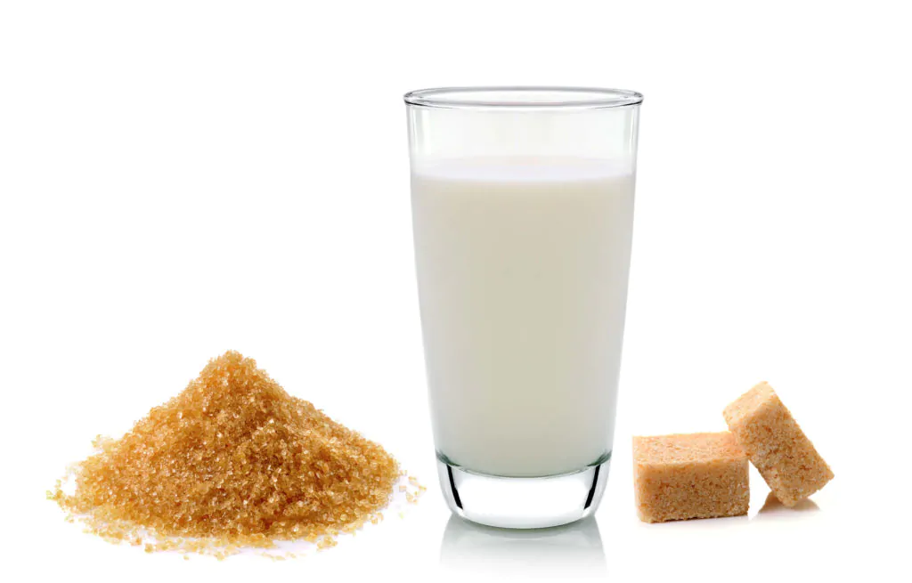 a glass of milk and cubes of sugars beside it