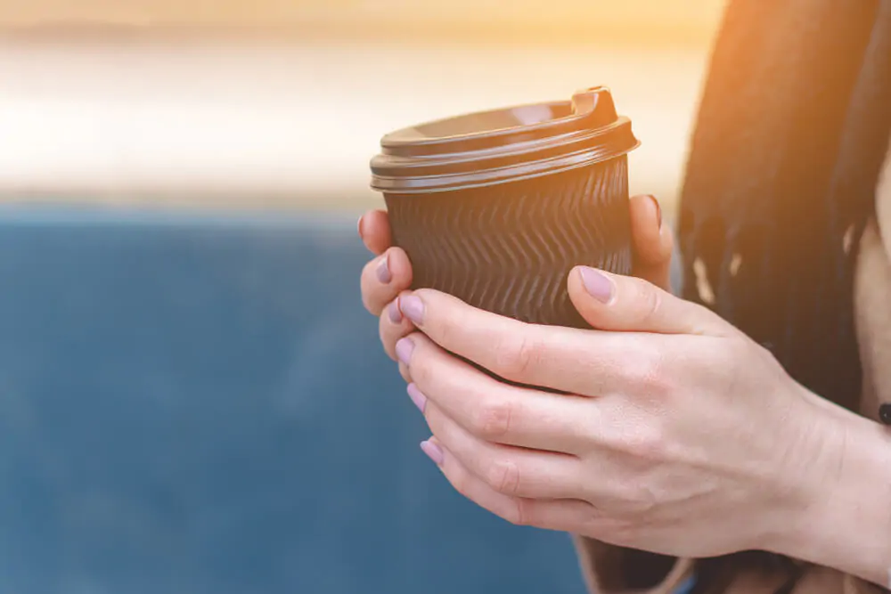 Female hand holding a black coffee cup 
