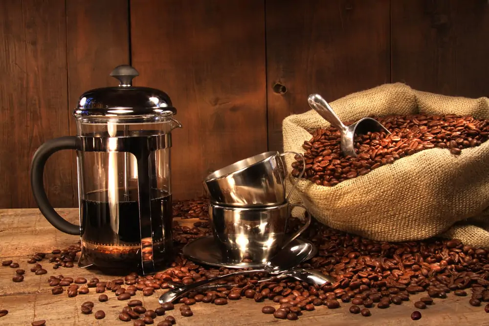 french press with a sack of coffee beans and stainless cups