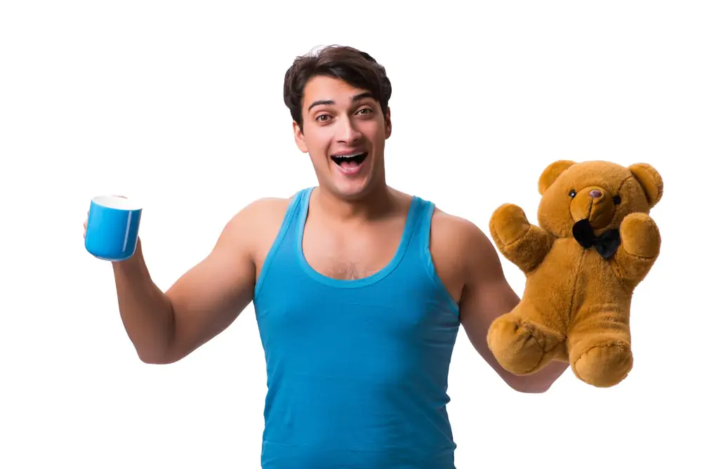 A man holding a teddy bear posing for the camera