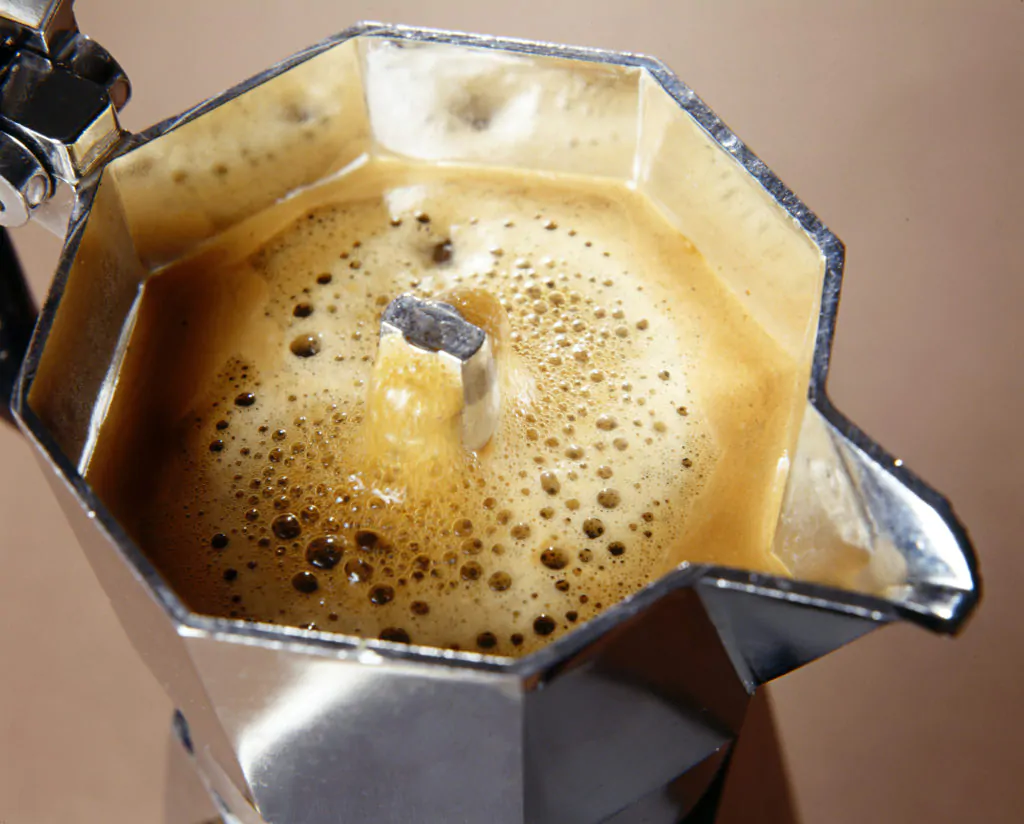 Frothy freshly percolated espresso coffee in a stovetop moka espresso pot
