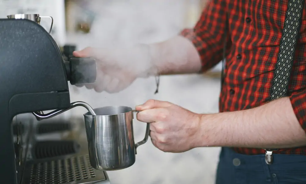 A man making hot coffee as evident by the smoke.
