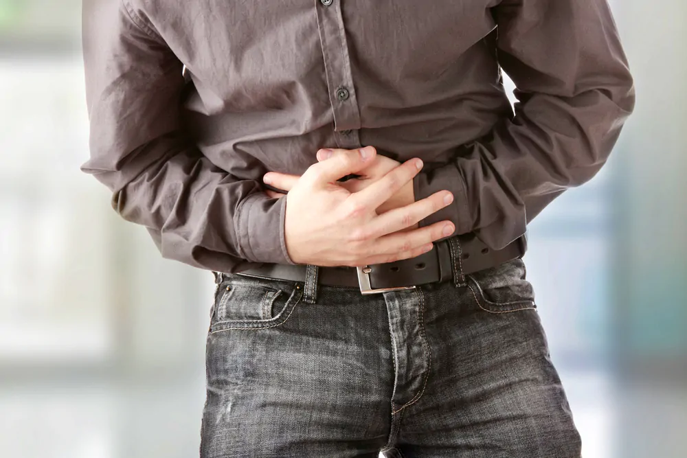 Does coffee upset your stomach - holding his stomach due to pain