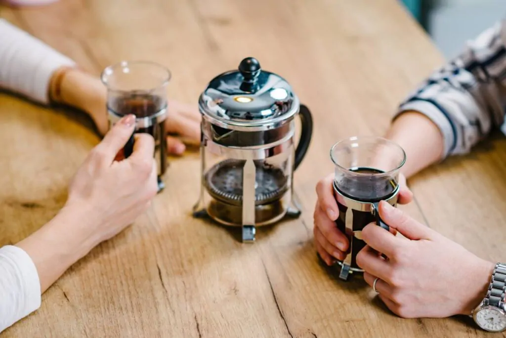 two people talking while drinking with the french press in the middle