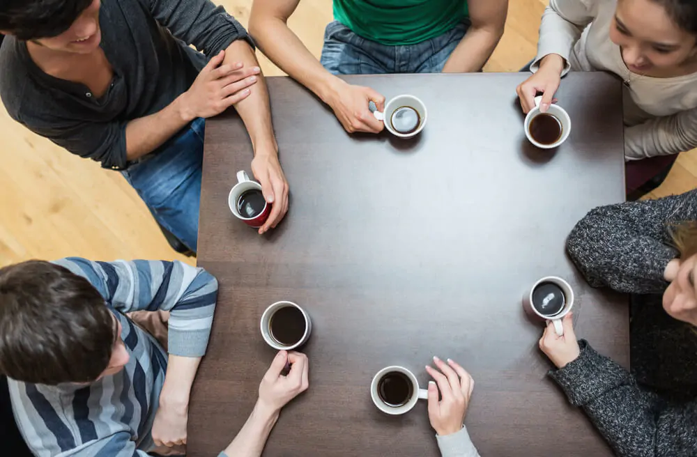 people sitting around a round table drinking coffee