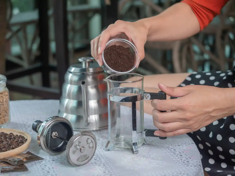pouring coarse ground coffee beans into a french press