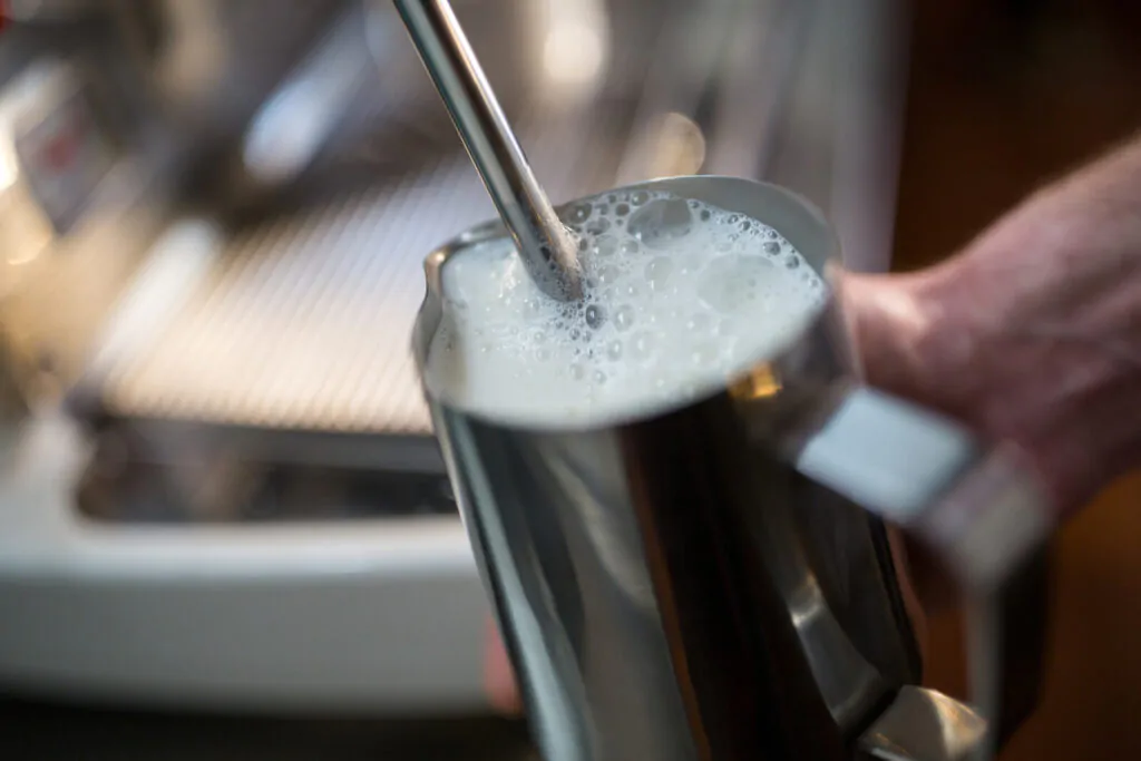 steaming milk at the coffee machine in restaurant