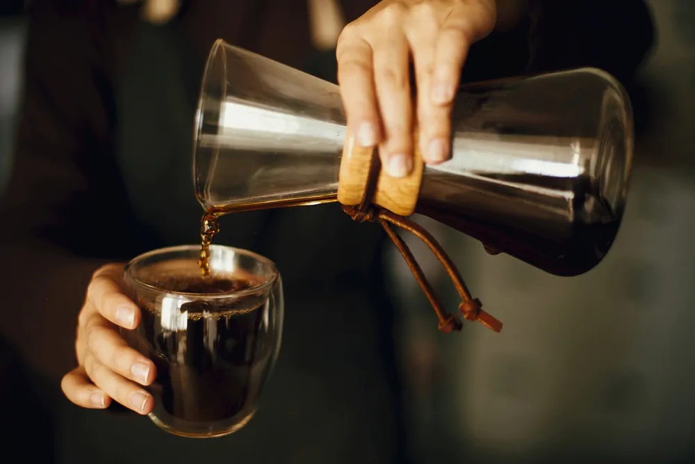 person pouring fresh black aromatic coffee