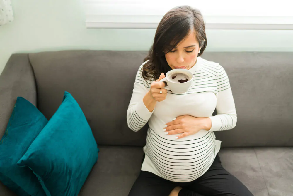 Decaffeinated coffee when pregnant - woman sitting on a couch while drinking coffee