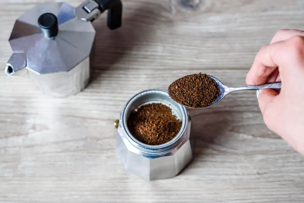 How many tablespoons per cup of coffee - taking a spoonful of coffee ground from a jar