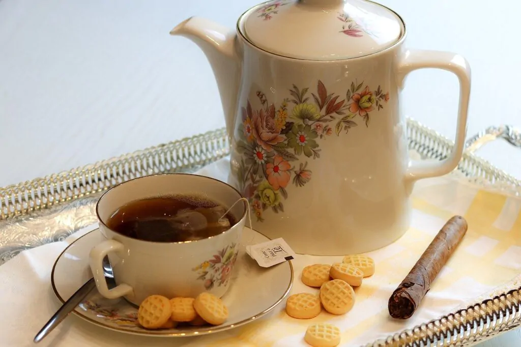 a cup of tea, a single tobacco, and biscuits in a food tray