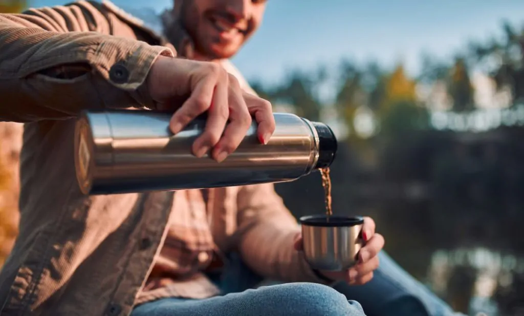 man pouring coffee in a coffee thermos