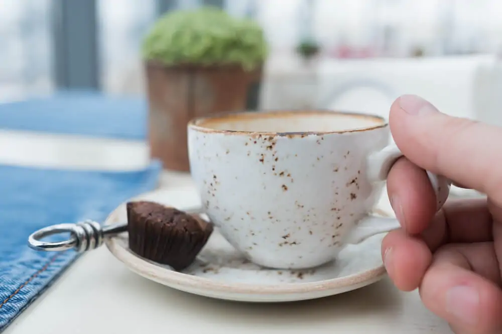 A hand holding a scratched coffee mug