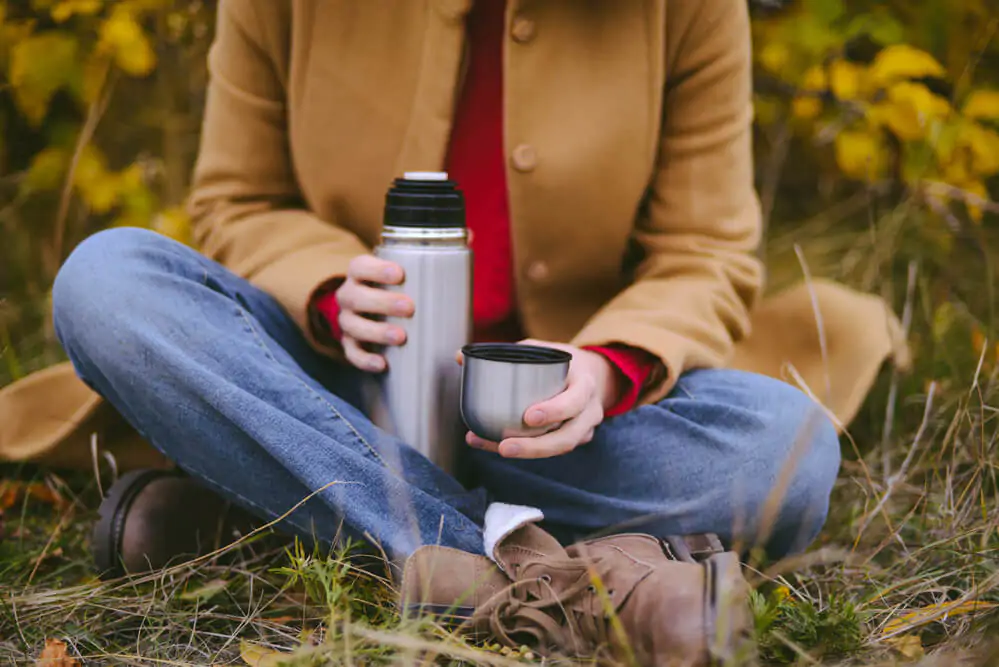 woman sitting and holding a coffee thermos