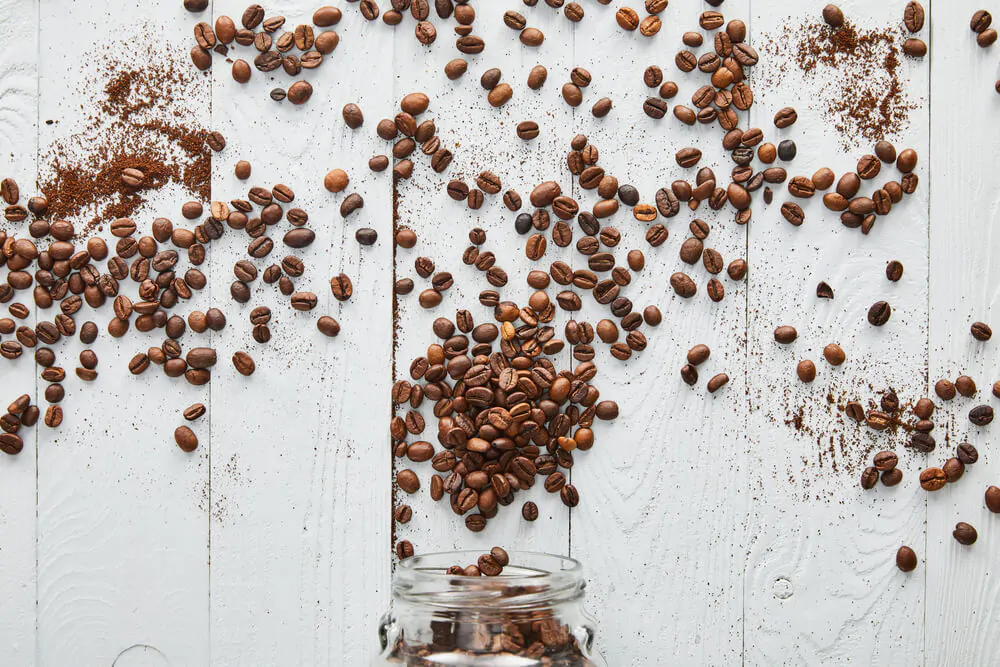 Coffee beans scattered on white wooden surface