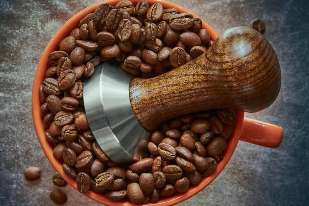 Coffee tamper in a cup with coffee beans