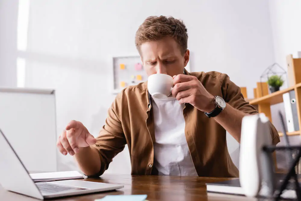 a businessman drinking coffee on his office - Why Does My Coffee Taste Burnt
