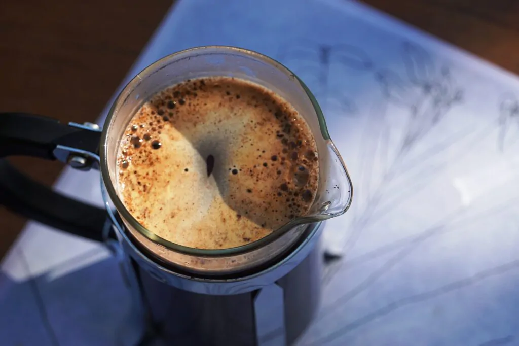 a freshly brewed coffee on a french press. bubbles are visible at the top