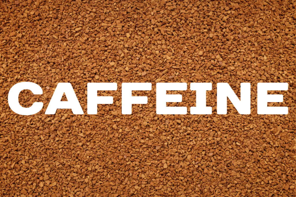 CAFFEINE text written over background of instant coffee granules