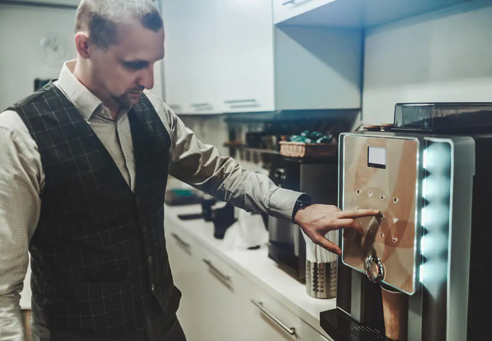 man using a smart coffee machine in his kitchen